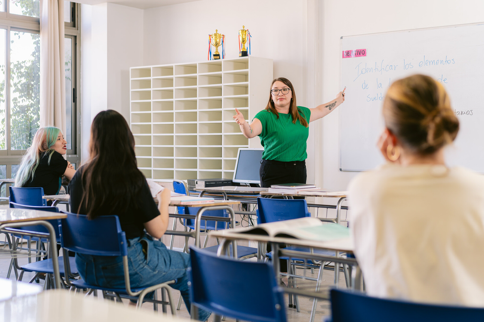 Profesora escribiendo en pizarra, vista desde estudiantes — Elige Educar Mineduc